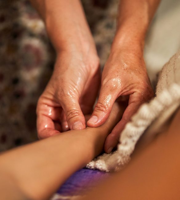 Crop faceless professional therapist massaging arm while spreading aromatic relaxing oil during procedure in salon